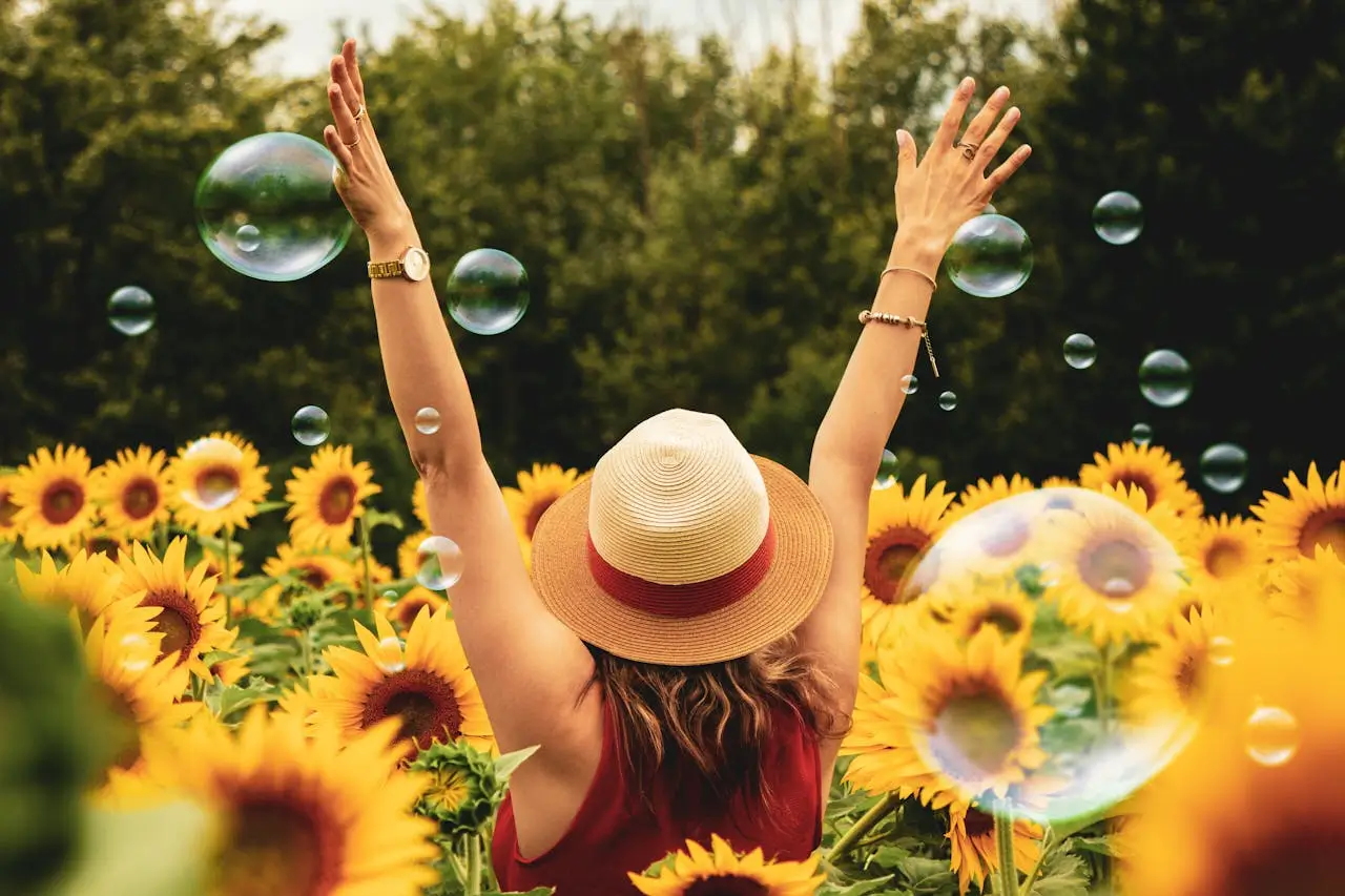 Donna in un campo di girasoli con le braccia alzate, simbolo degli Ordini del Successo: appartenenza, equilibrio e realizzazione personale.