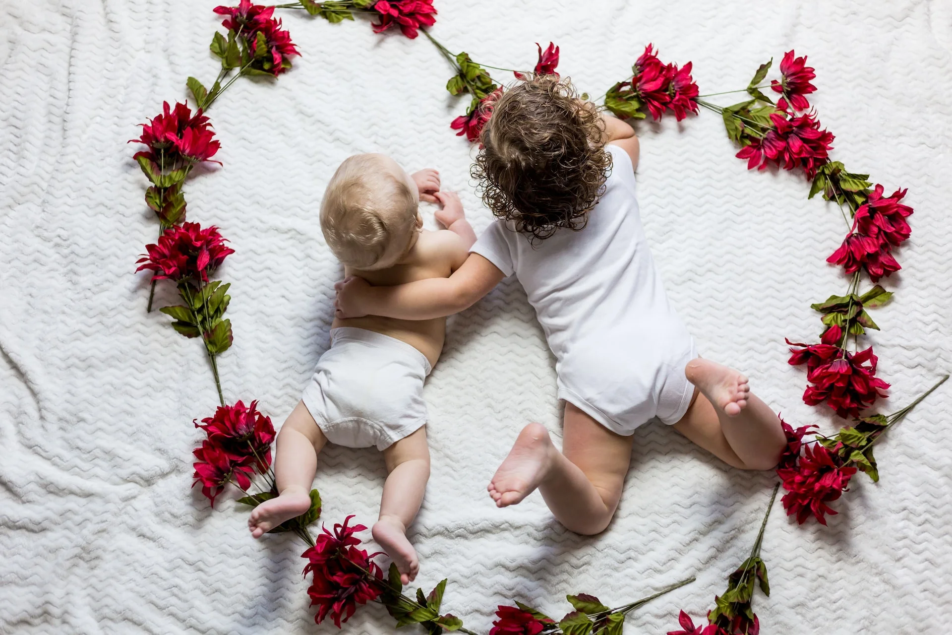 Il tema dei fratelli è rappresentato nell'immagine grazie a due bimbi racchiusi in una bellissima ghirlanda di fiori rossi a forma di cuore