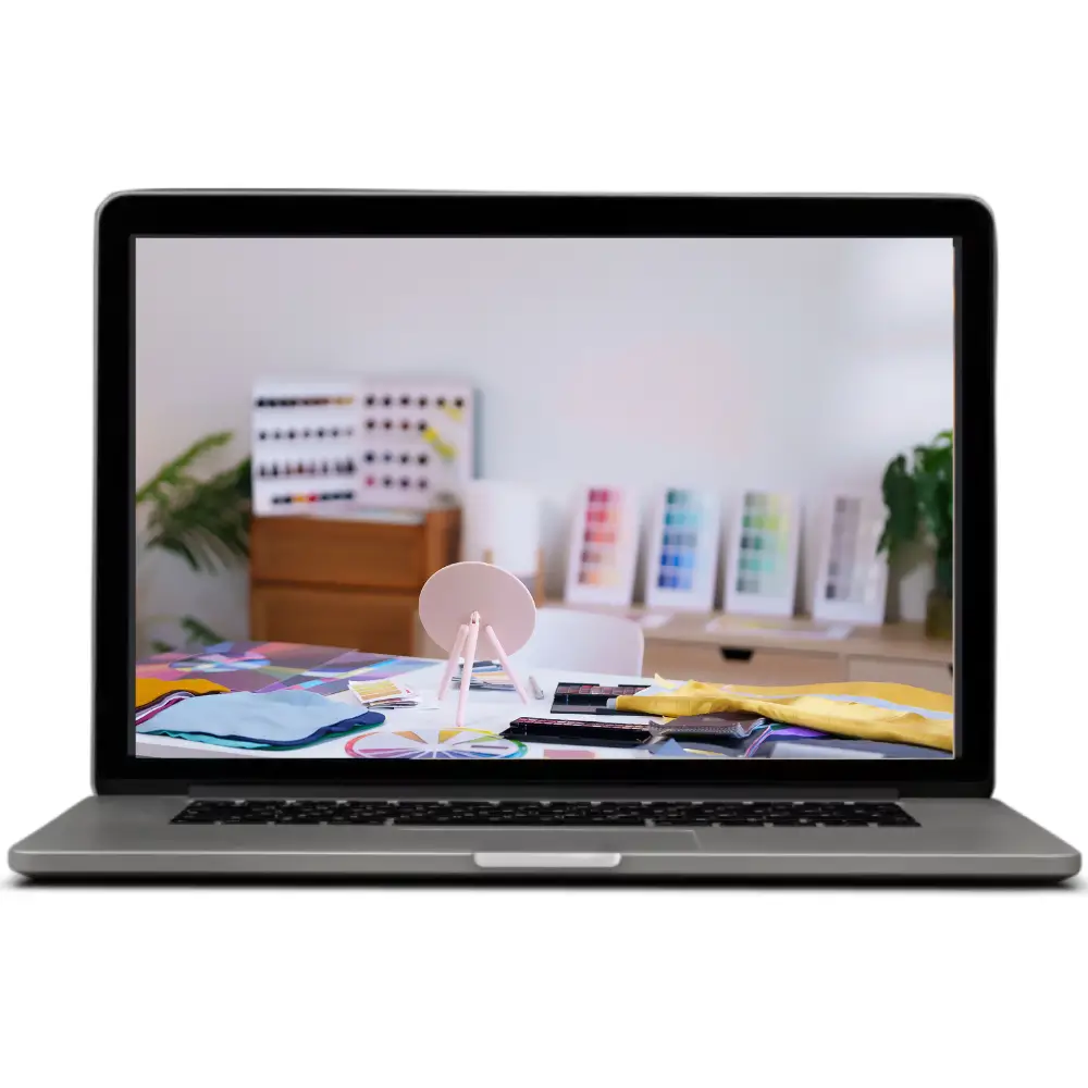 Computer portatile con schermata di un ambiente creativo, con materiali colorati e strumenti disposti su un tavolo, a rappresentare una masterclass preregistrata sul personal branding.
