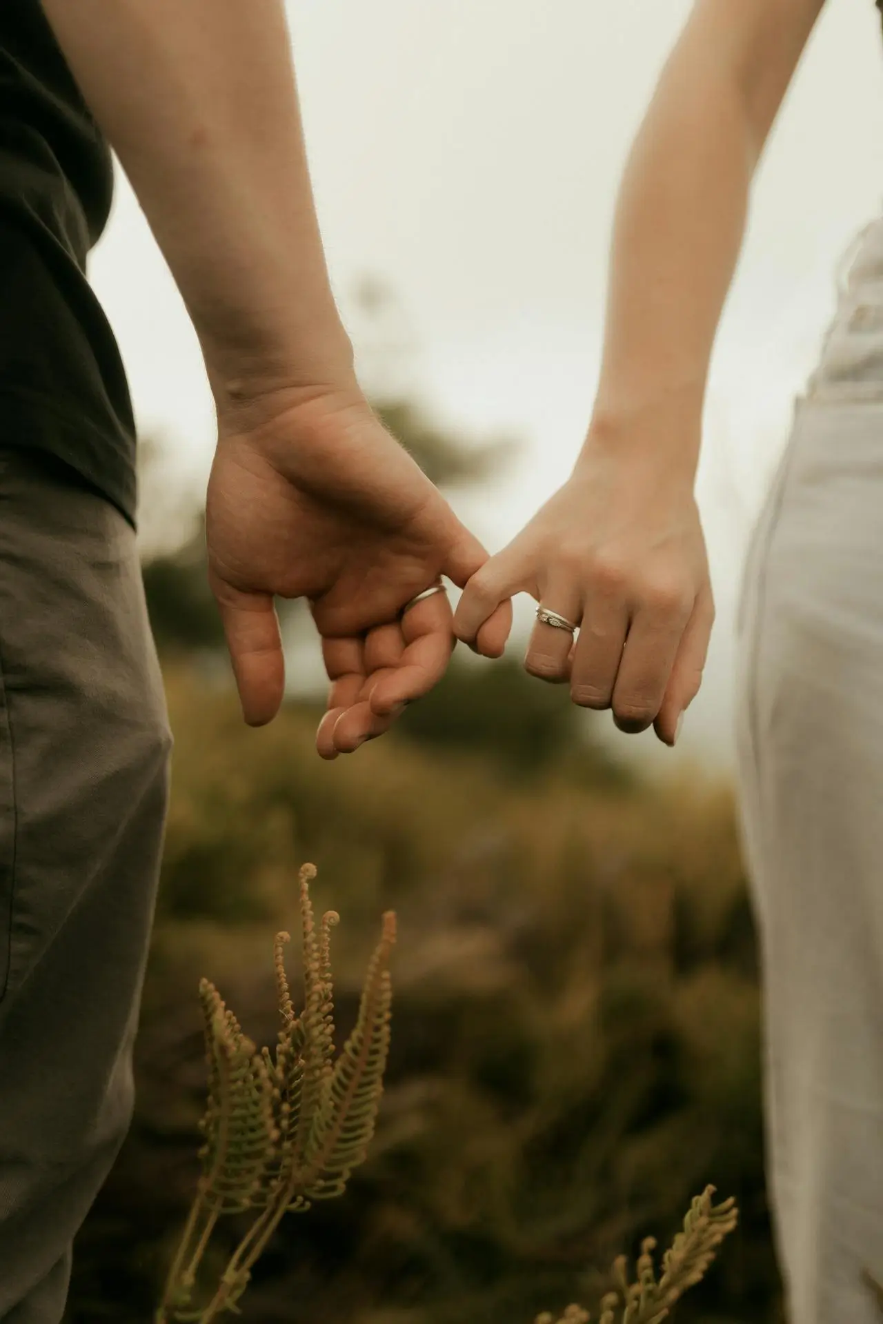 Due persone che si tengono per mano in modo delicato all’aperto
