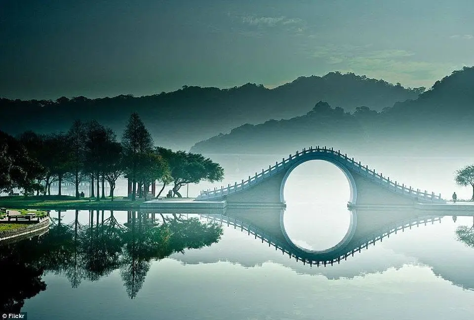 Ponte ad arco riflesso nell’acqua, simbolo di passaggio, trasformazione e rinascita
